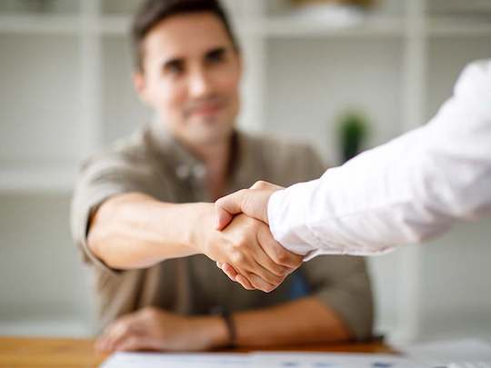 Hjælpsom Piranya medarbejder i hvid skjorte trykker mandlig kunde i hånden